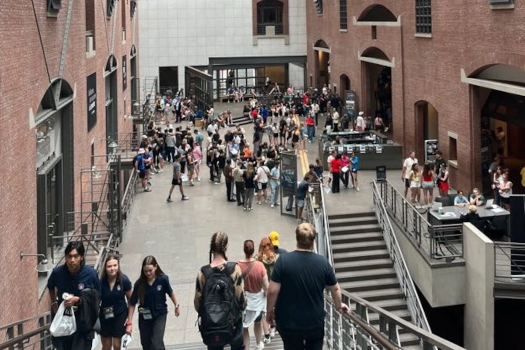 Menschenstrom in der großen Backsteinhalle des USHMM: Treppen, Geländer und Gruppen von Besuchern.