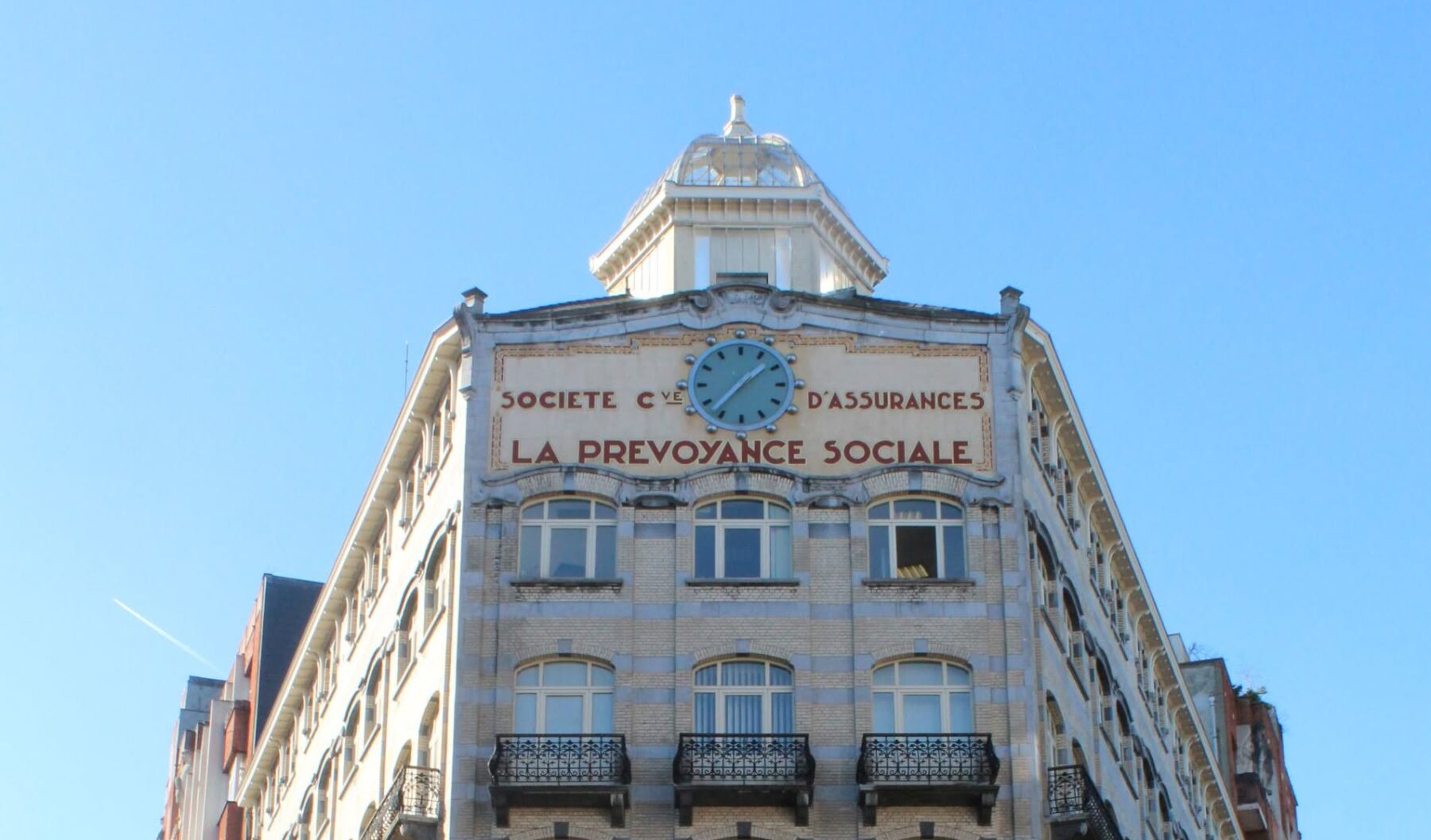 CEGESOMA-Gebäude Brüssel: Eckhaus mit Uhr, Schriftzug 'La Prévoyance Sociale' und schmiedeeiserne Balkone.