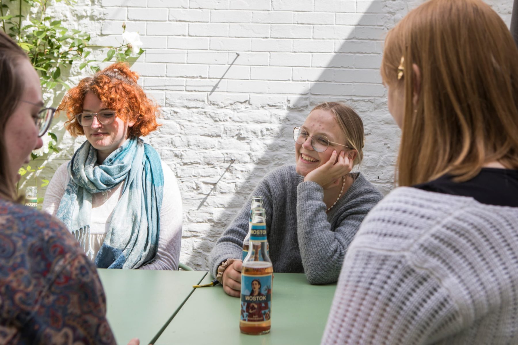 Freiwillige in Brüssel sitzen draußen an einem Tisch und unterhalten sich fröhlich.