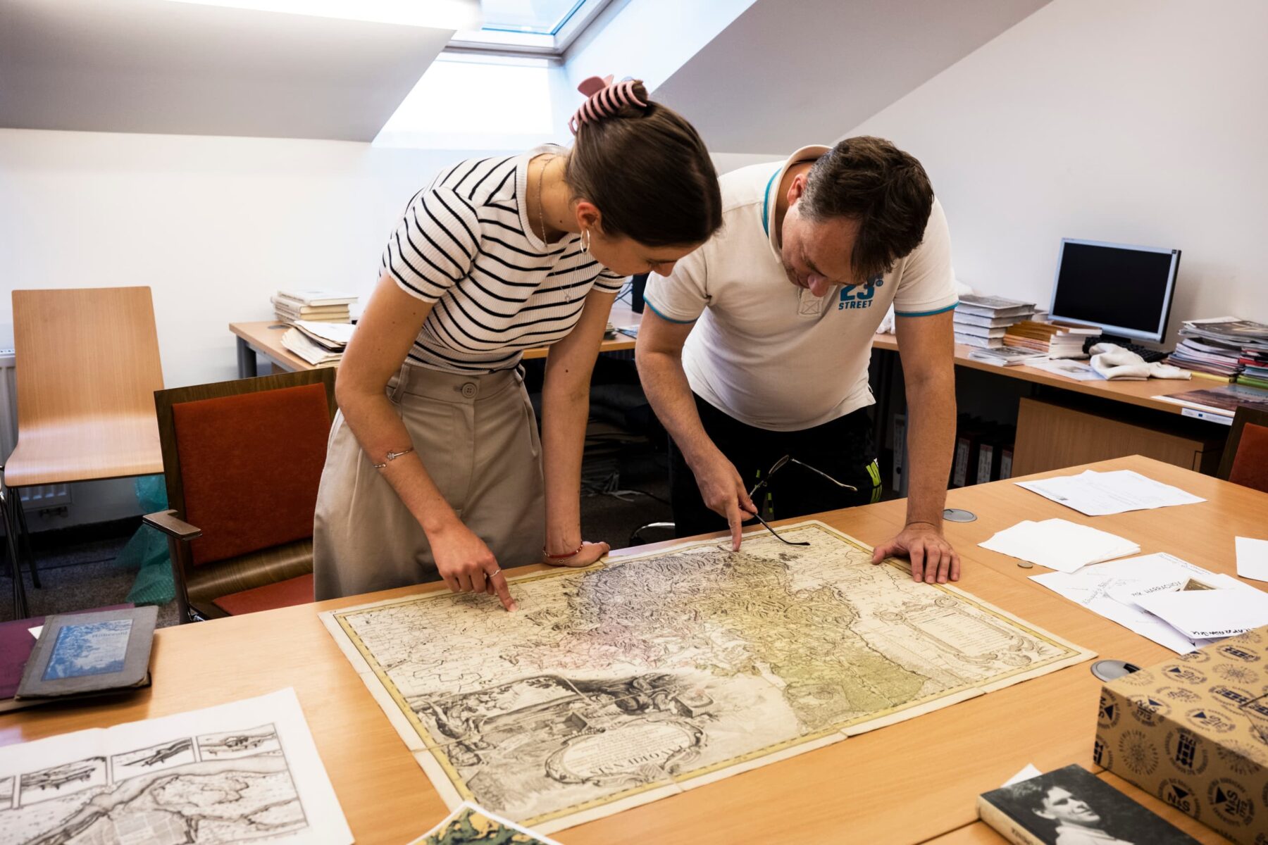 Freiwillige und Mitarbeiter im Collegium Bohemicum in Ústí nad Labem beugen sich über eine alte kolorierte Landkarte.