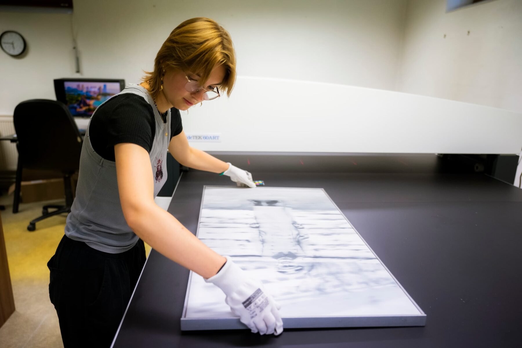 Eine Freiwillige legt mit weißen Handschuhen ein gerahmtes Foto auf einen Flachbettscanner in der Gedenkstätte Lidice.