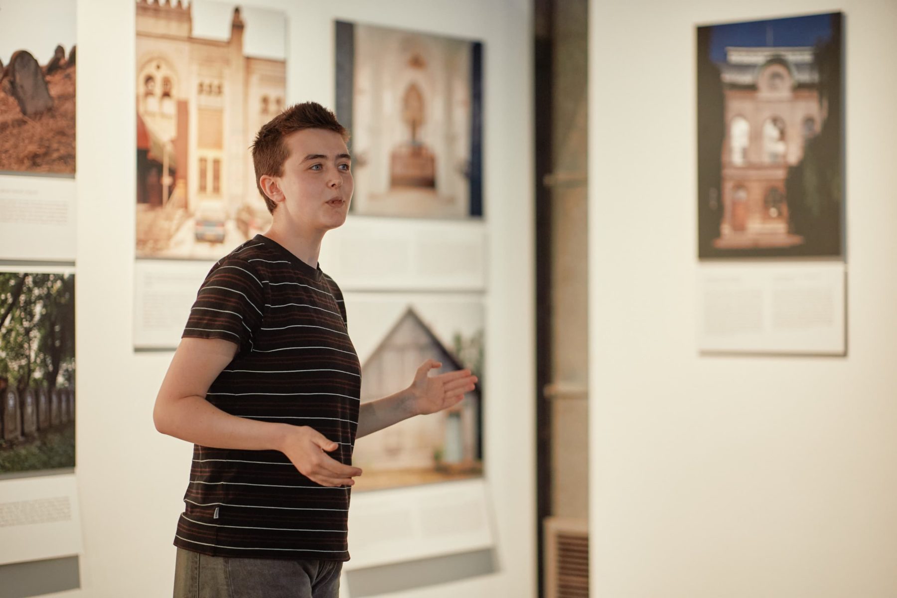 Person erklärt Ausstellung im Jüdischen Museum Krakau. Bilder von Gebäuden im Hintergrund.