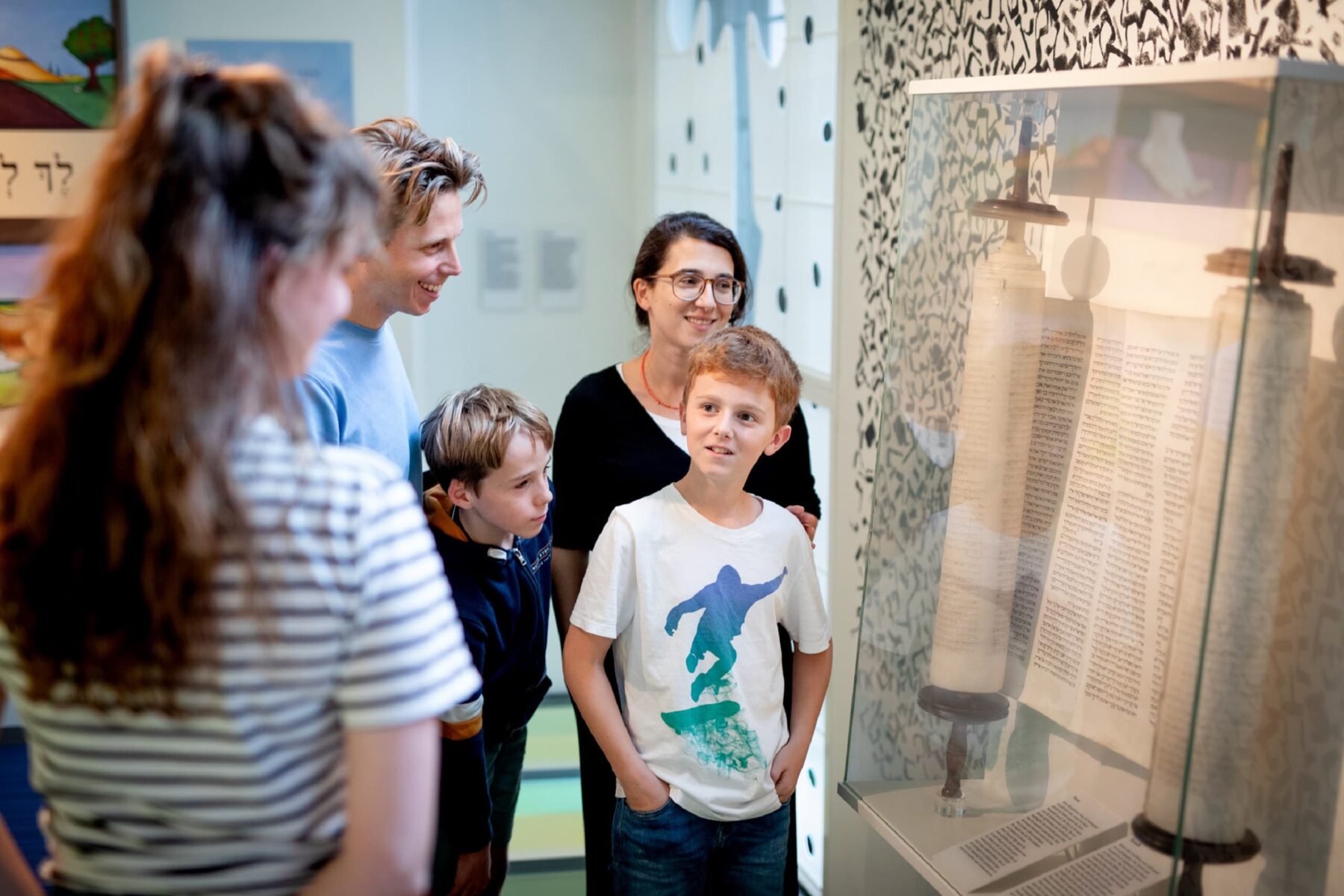 Familie mit Kindern betrachtet Thorarolle in Glasvitrine bei einer Familienführung im Jüdischen Museum Amsterdam