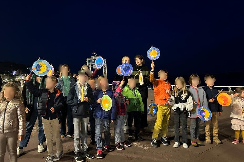Gruppe Kinder mit bunten Papier-Laternen am Abend beim ASF-Laternenlauf auf Nizzaer Promenade.