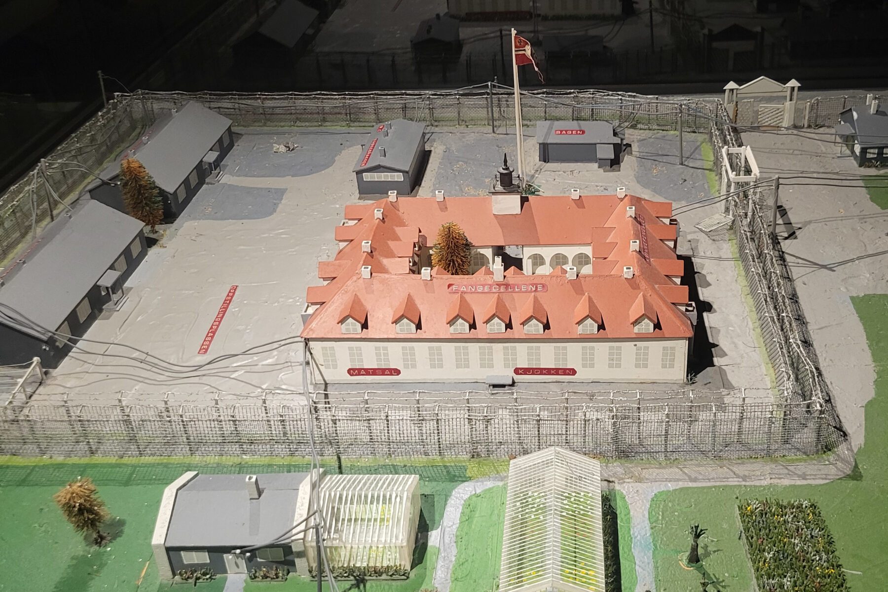 Modell des Falstad-Zentrums: rechteckiges Gebäude mit rotem Dach, Innenhof, Stacheldrahtzaun und Nebengebäuden.