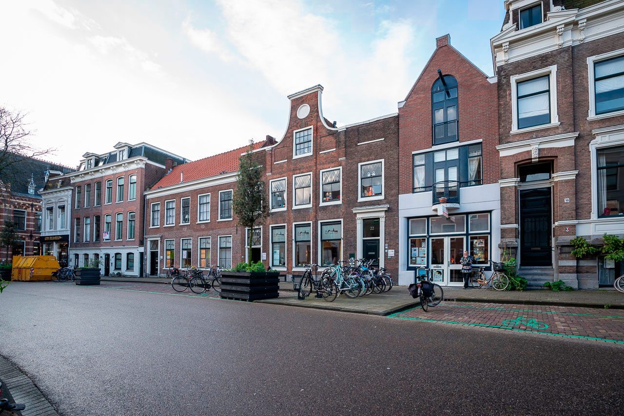 Reihen historischer Backsteinhäuser mit Giebeln und geparkten Fahrrädern an nasser Straße in Haarlem, Niederlande.