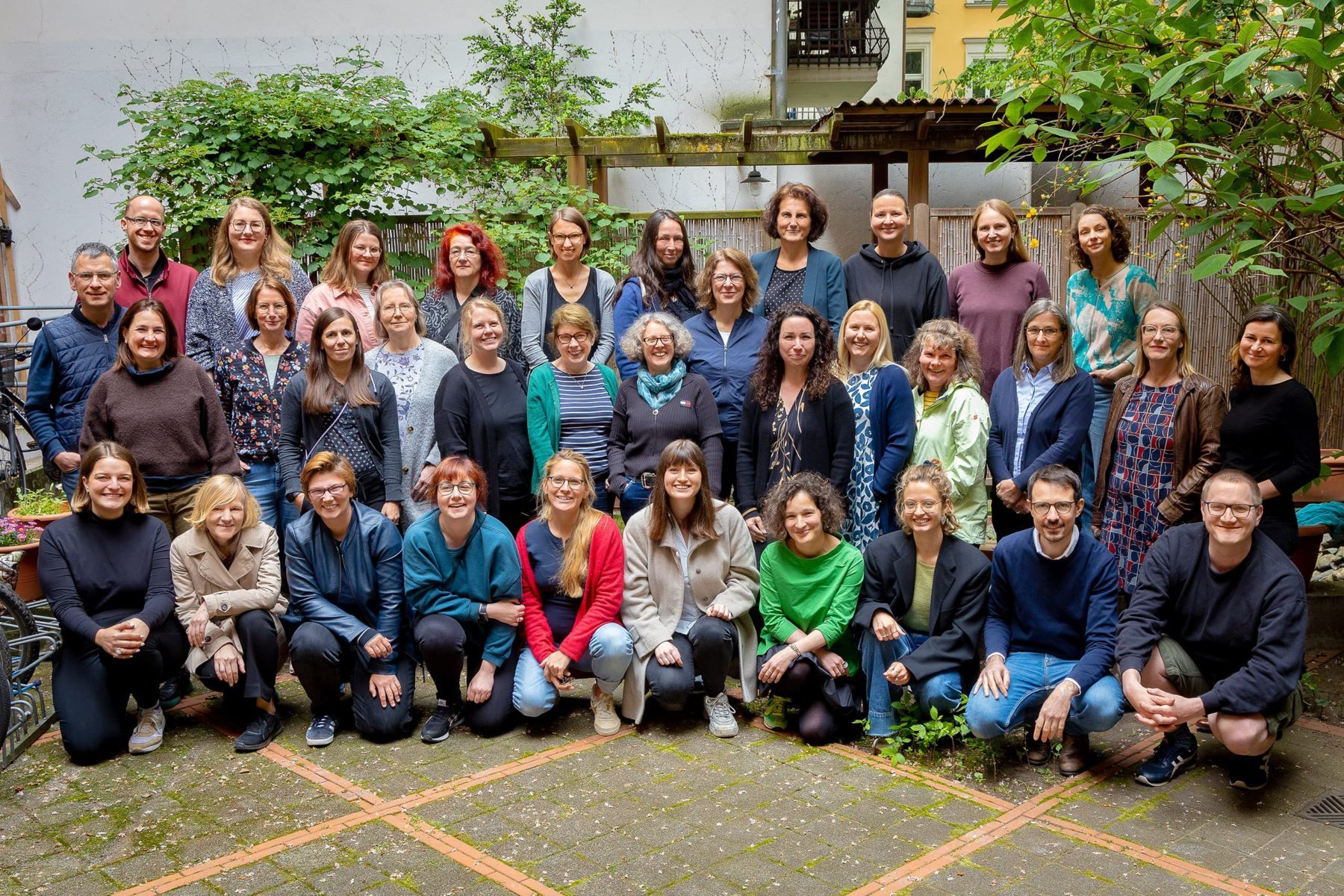 Eine große Gruppe von Menschen sitzt und steht im Innenhof. Das sind das ASF-Team im Jahr 2023.